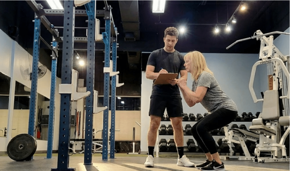 Fitness assessment session with trainer evaluating client movement and strength