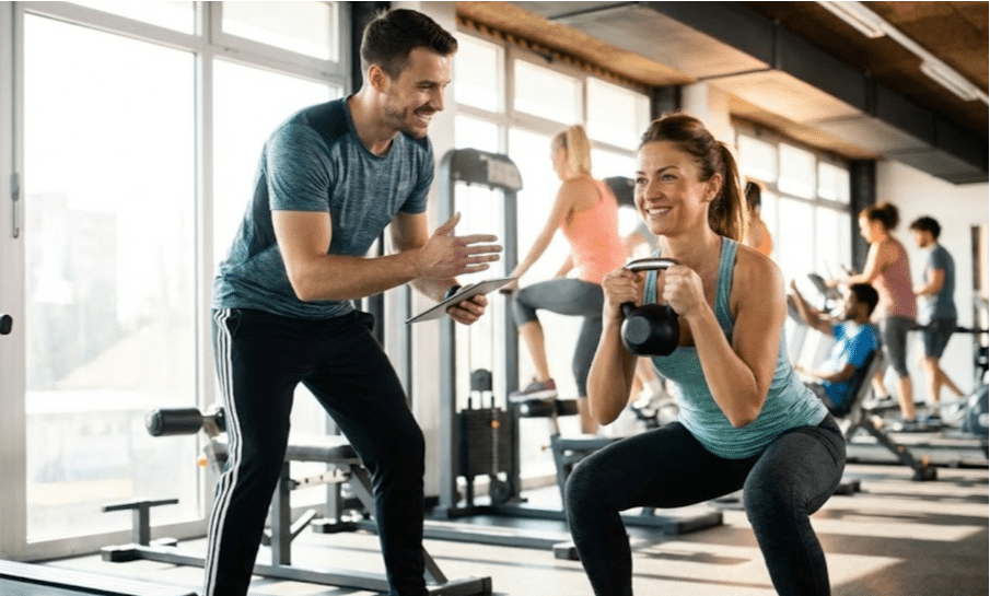 Personal trainer coaching client through bone-strengthening squat exercise